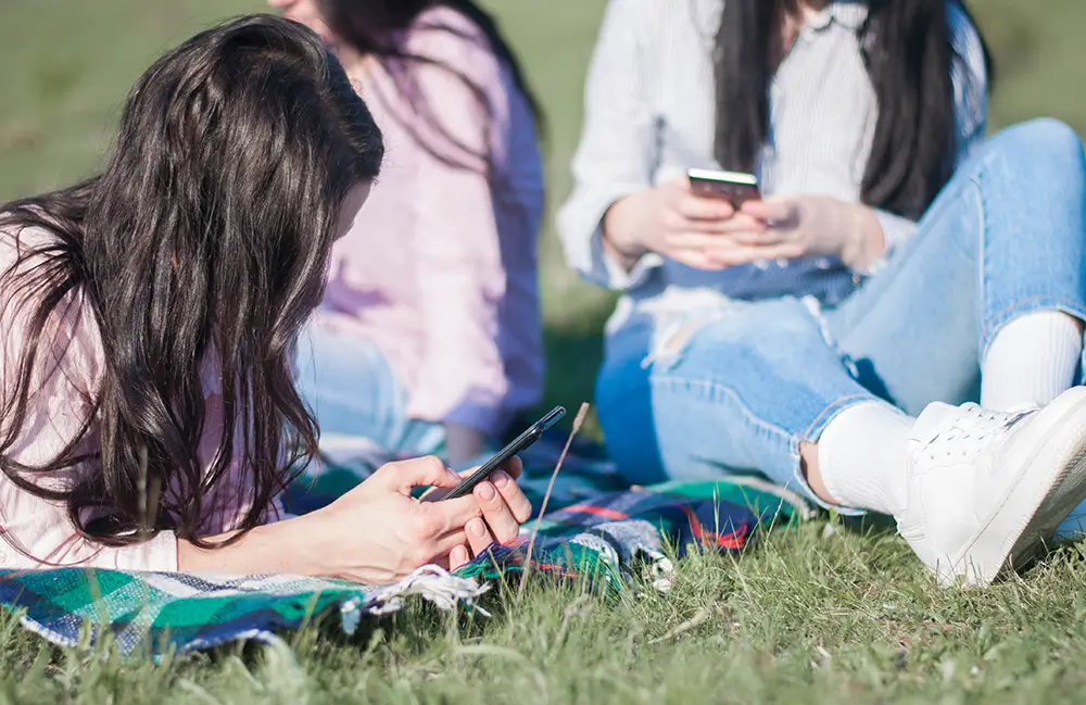 Varias niñas observan su smartphone en un parque.