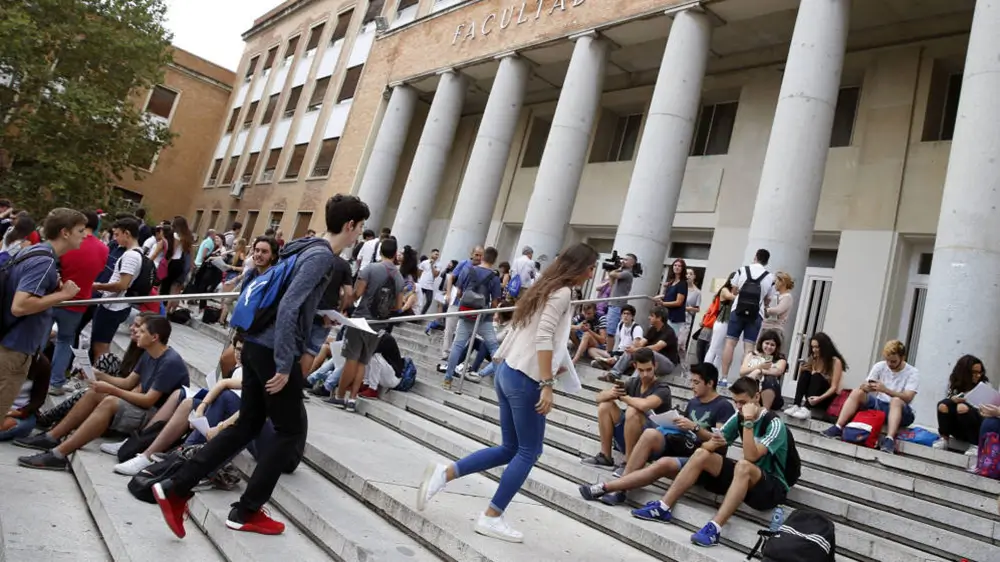 Numerosos jóvenes frente a un edificio universitario.