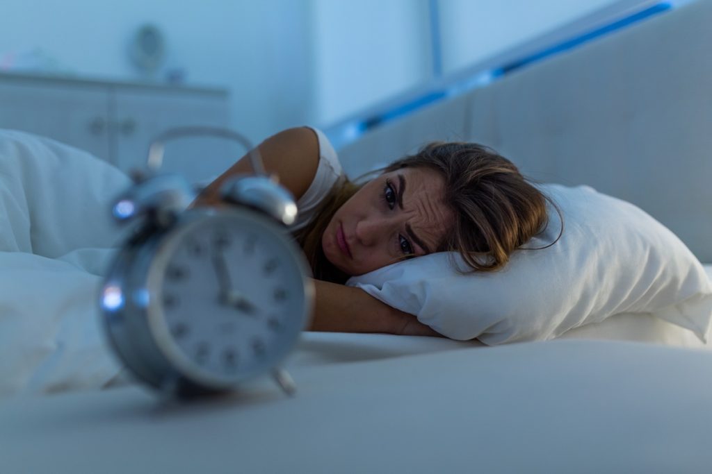 Mujer tumbada en una cama mirando un reloj