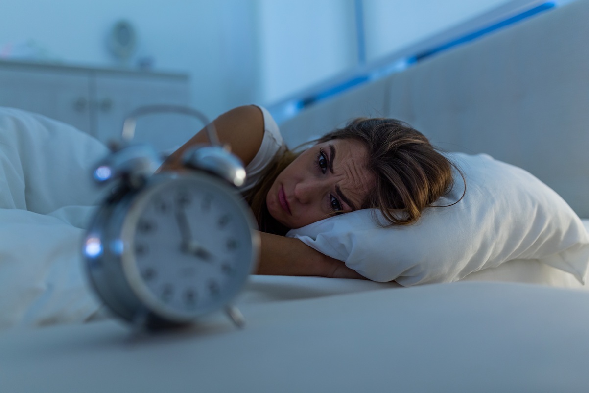 Mujer tumbada en una cama mirando un reloj