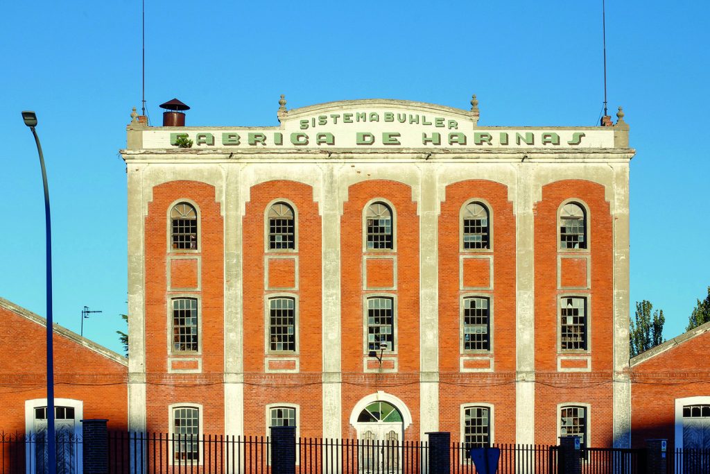 Un edificio de ladrillo rojo con un cartel anticuado que pone "Fábrica de Harinas", en Olmedo