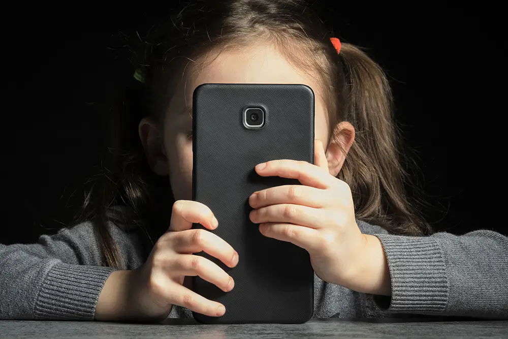 Una niña observa la pantalla de un teléfono móvil.