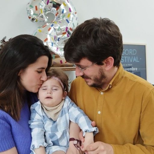 Sobre la imagen una pareja feliz, besando en el moflete a u su hija.
