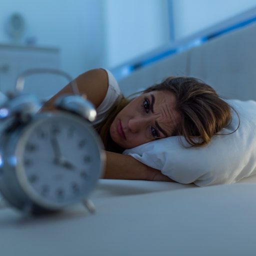 Mujer tumbada en una cama mirando un reloj