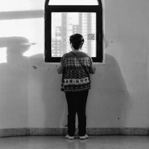 Persona de espaldas frente a una ventana en un espacio interior.