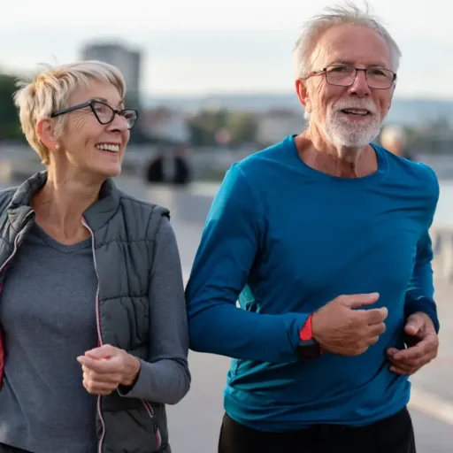 Dos personas mayores practican deporte al aire libre en un entorno urbano.