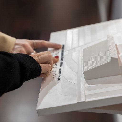 Manos tocando una de las maquetas accesibles de la exposición