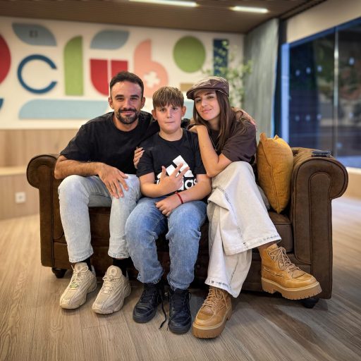 IlloJuan y Lola Índigo con uno de los niños de Fundación Juegaterapia, sentados en un sofá