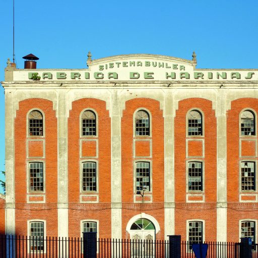 Un edificio de ladrillo rojo con un cartel anticuado que pone "Fábrica de Harinas", en Olmedo
