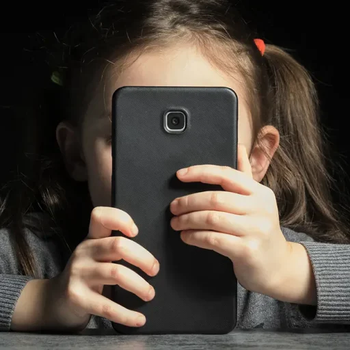 Una niña observa la pantalla de un teléfono móvil.